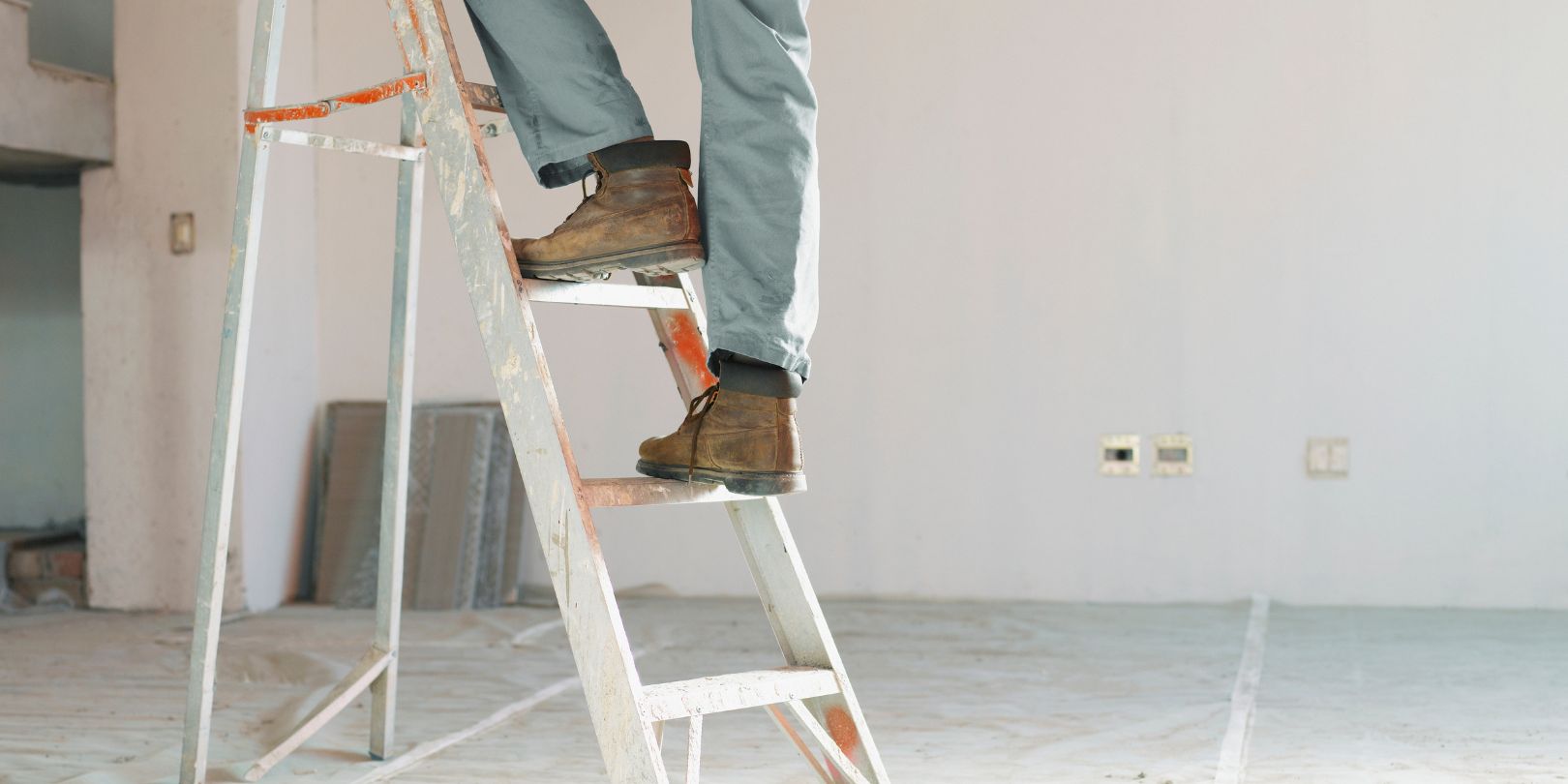 Man climbing ladder in unfinished room